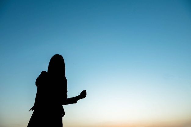 Silhouette woman hands up in the sky with happiness.