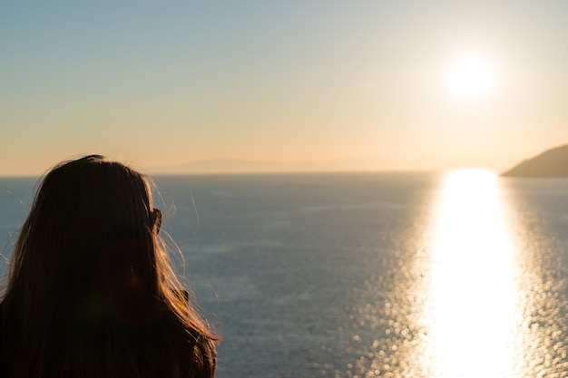 Foto la siluetta della donna sta guardando il tramonto sul mare e sulle scogliere