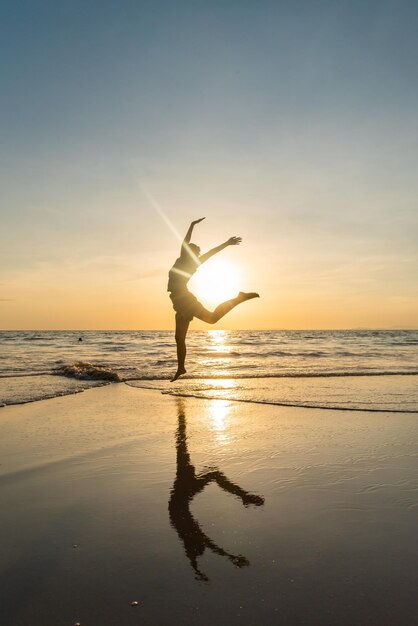 Foto silhouette donna salta al tramonto all'isola di phayam ranong thailandia