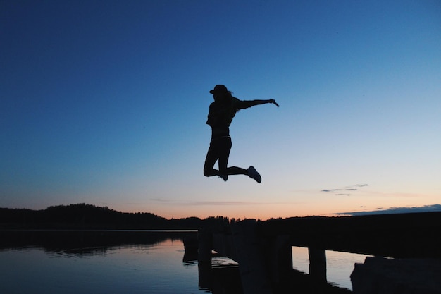 写真 夕暮れの空に飛び込む女性のシルエット