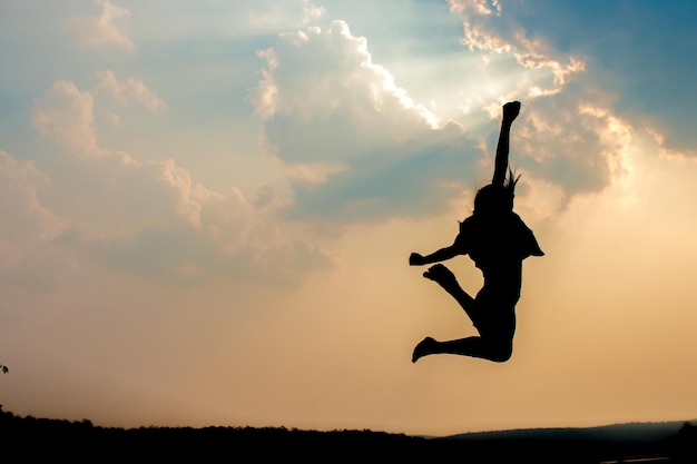 Silhouette woman jumping against sky during sunset