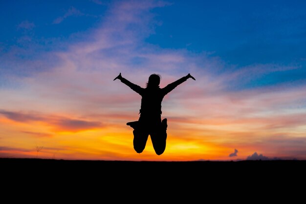 Silhouette woman jumping happily relieved.