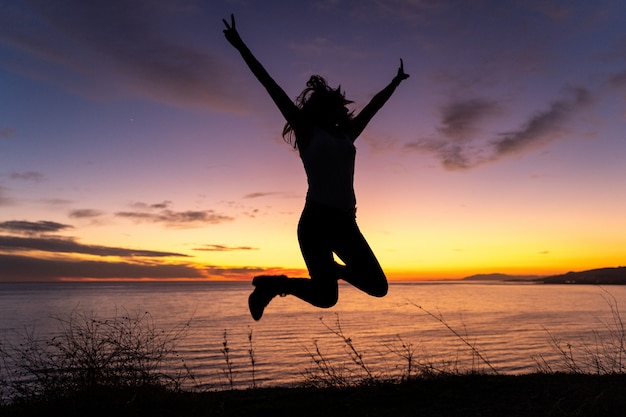 Silhouette of woman jumping and having fun at the beach