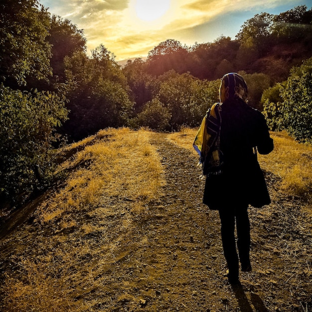 Photo silhouette of woman on landscape at sunset