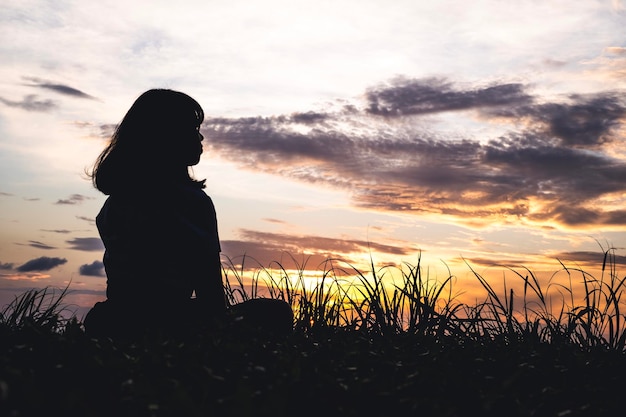 Photo silhouette woman looking at field against sky during sunset