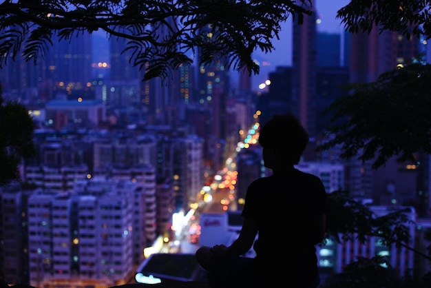 Foto silhouette donna con vista sulla città illuminata dalla terrazza di notte