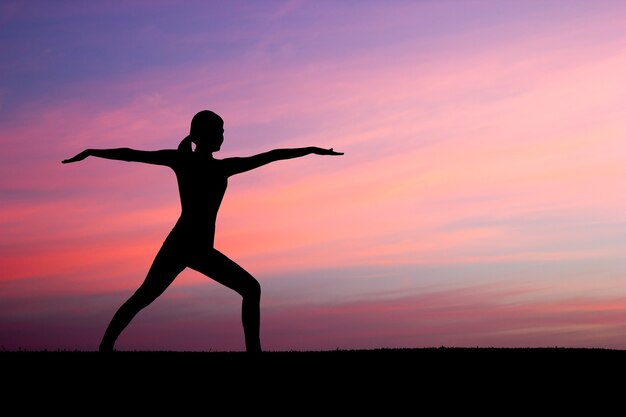 Силуэт женщины, практикующие воинскую йогу на закате