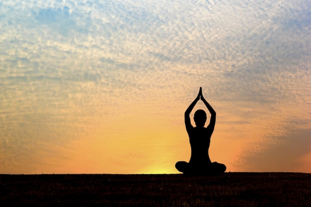 Silhouette of woman practicing yoga at sunrise