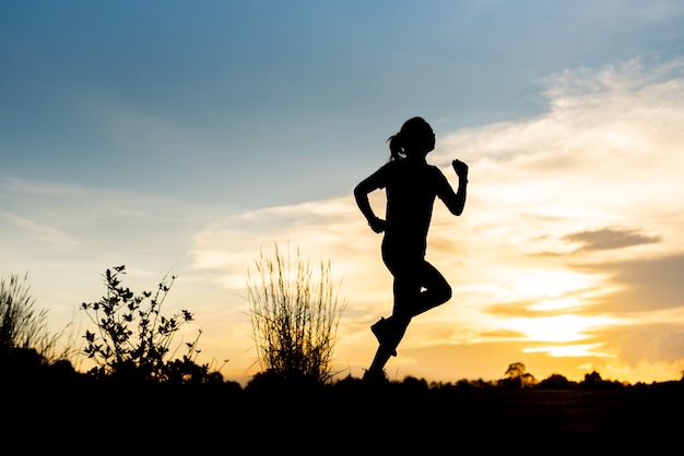 Silhouette woman running alone at beautiful sunset in the park.