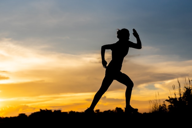 Silhouette donna che corre da sola al bel tramonto nel parco.