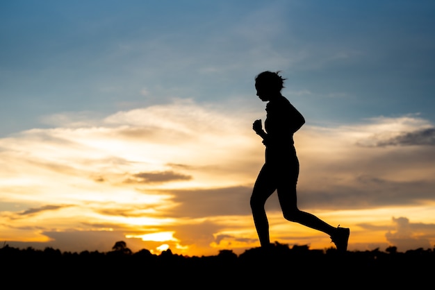 Silhouette woman running alone at beautiful sunset in the park.