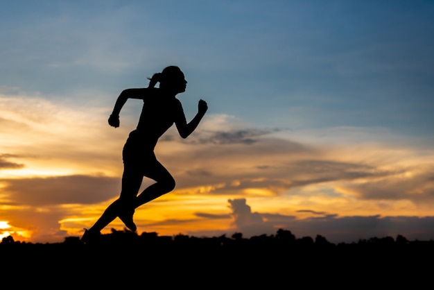 Silhouette woman running alone at beautiful sunset in the park.