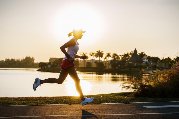 Photo silhouette woman running at lakeside against sunset