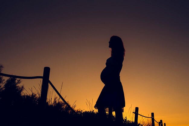 Silhouette woman standing against clear sky during sunset