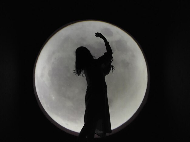 Foto silhouette donna in piedi contro la luna di notte