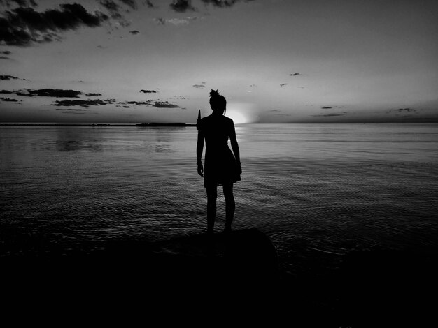 Foto silhouette donna in piedi contro il mare sulla spiaggia