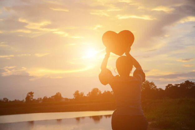 写真 夕暮れの空に向かって立っている女性のシルエット