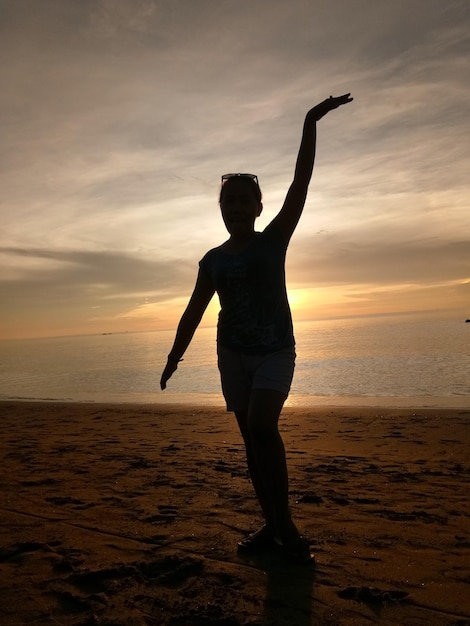 Photo silhouette woman standing on beach against sky during sunset