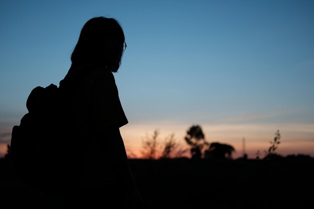 Photo silhouette woman standing on field against sky during sunset