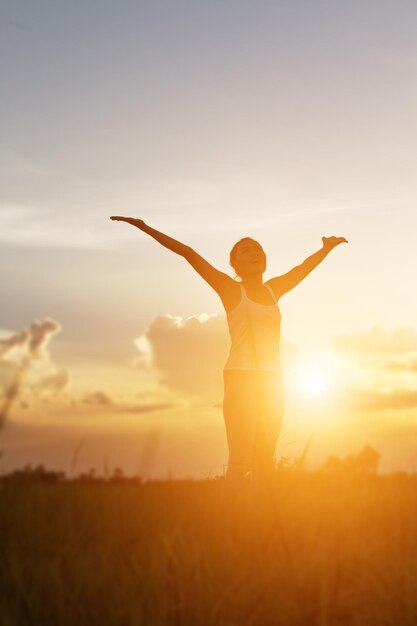 Silhouette woman standing on field against sky during sunset