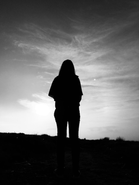 Photo silhouette woman standing on field against sky during sunset