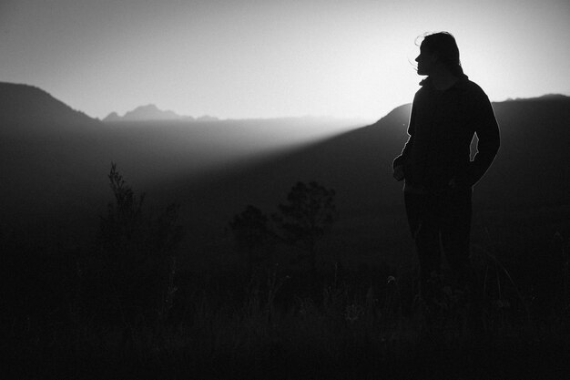 Silhouette woman standing on field against sky during sunset