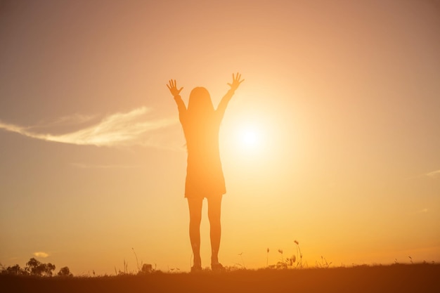 Silhouette woman standing on field against sky during sunset