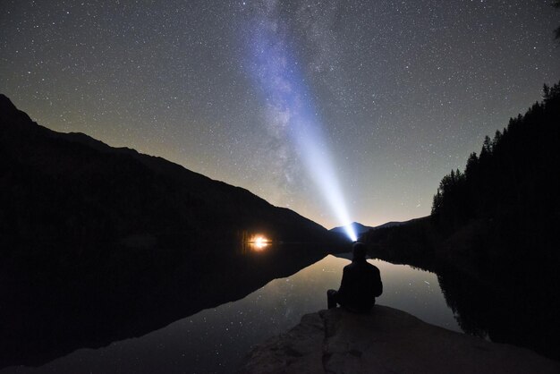 Silhouette woman standing on mountain against sky at night