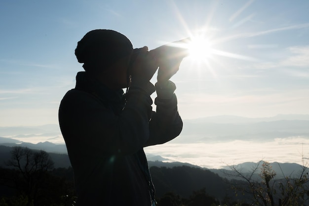 写真 夕暮れの空に照らされた山の上に立っている女性のシルエット