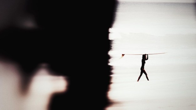 Foto silhouette donna in piedi alla luce del sole dopo il surf