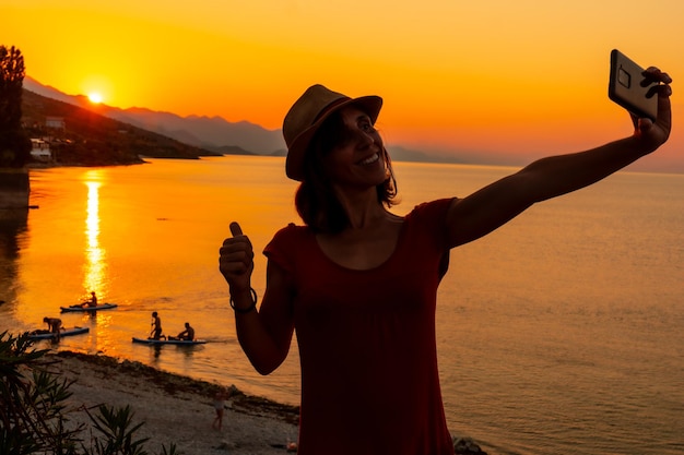 Silhouette of a woman taking a selfie at sunset at Shkoder lake in Shiroka municipality summer vacation Albania