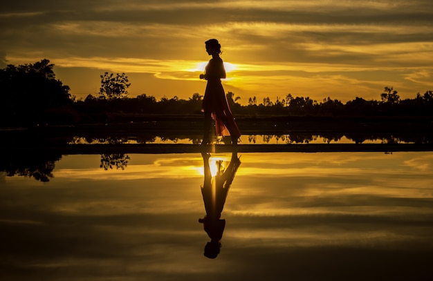 Silhouette of the woman walking at the beach during beautiful sunset