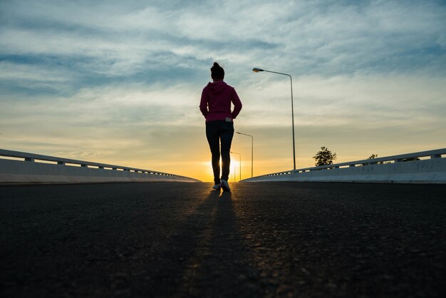 夕暮れ時の街を歩くシルエットの女性。