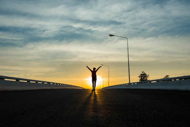 Silhouette woman walking on the street at sunset.