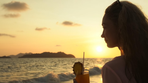 シルエットの女性の背景にビーチで夕日を歩く