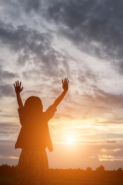 Foto silhouette donna con le braccia tese in piedi contro il cielo durante il tramonto