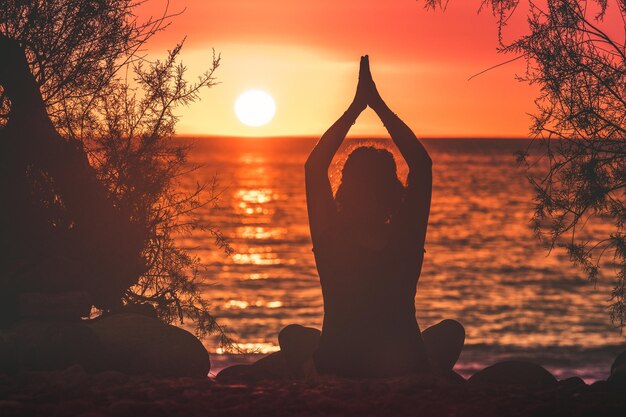 Foto silhouette di donna con le braccia alzate contro il cielo durante il tramonto