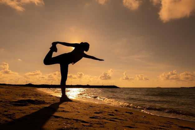 Silhouette woman yoga on the beach sunset. Sport and healthy lifestyle. Fresh start of day and recreation.