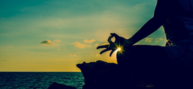 Yoga della donna della siluetta sul tramonto della montagna. nuovo inizio di giornata e stile di vita sano.