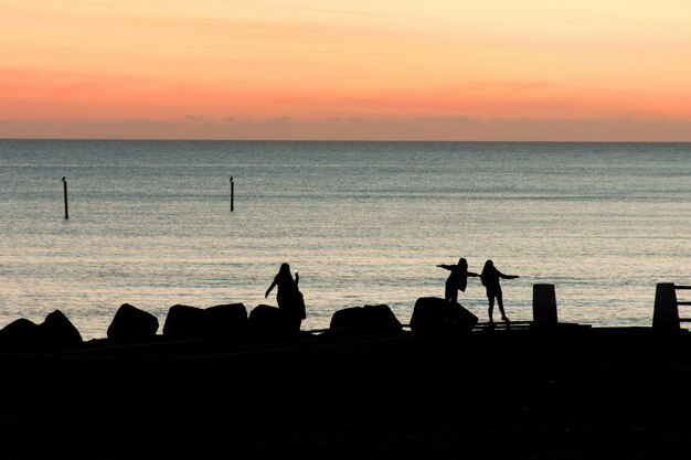 사진 해가 지는 동안 하늘을 배경으로 해변에 있는 여성들의 실루
