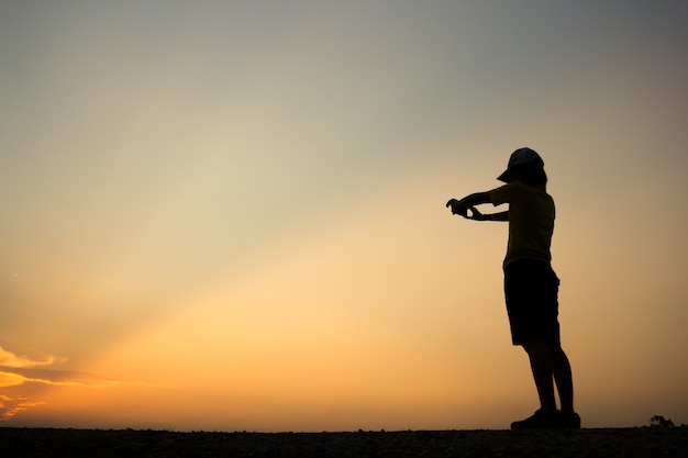 女性のシルエットは美しい夕日写真を撮っています。