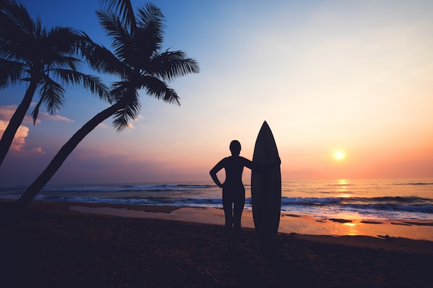 Silhouette women surfer on tropical beach at sunset. landscape of summer beach and palm tree at sunset. vintage color tone