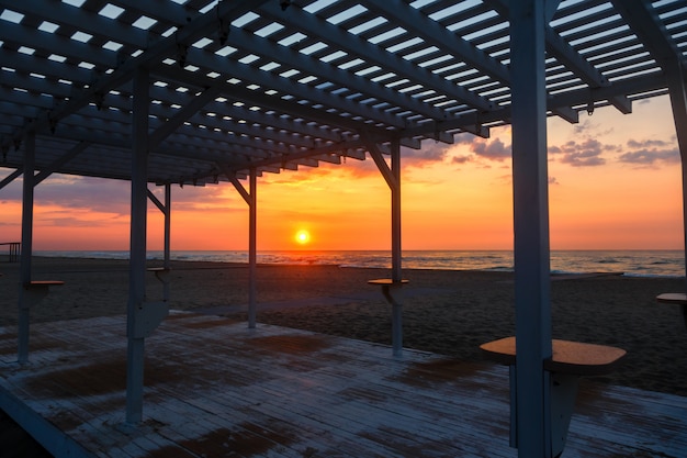 Silhouette of a wooden gazebo at sunset on a deserted beach