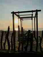 Photo silhouette wooden posts on beach against sky during sunset