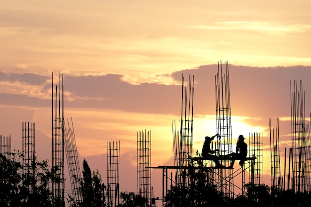 Silhouette of worker on safety stand from high ground and steel rod at Construction site.