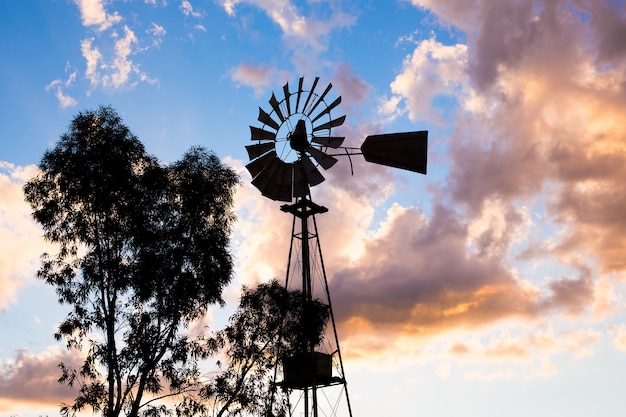 Silhouette of a working vintage country Windmill in sunset light or twilight.