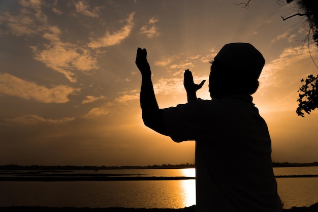 Silhouette Young asian muslim man praying on sunsetRamadan festival concept