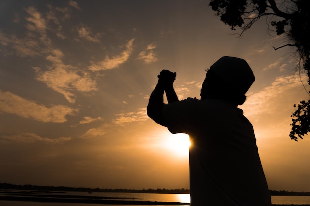 Silhouette giovane uomo musulmano asiatico che prega sul concetto di festival del tramontoramadan