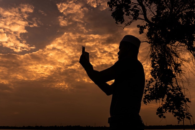 Silhouette Young asian muslim man praying on sunsetRamadan festival concept