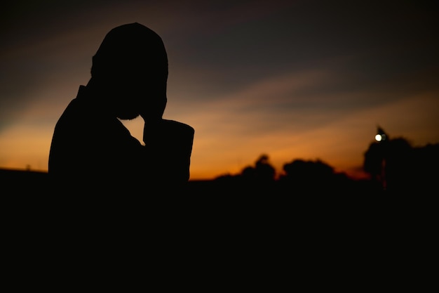 Silhouette giovane uomo musulmano asiatico che prega sul concetto di festival del tramontoramadan